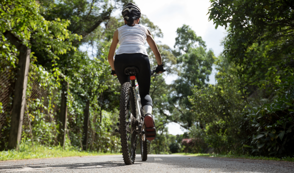 Femme roulant sur une piste cyclable dans un boisé